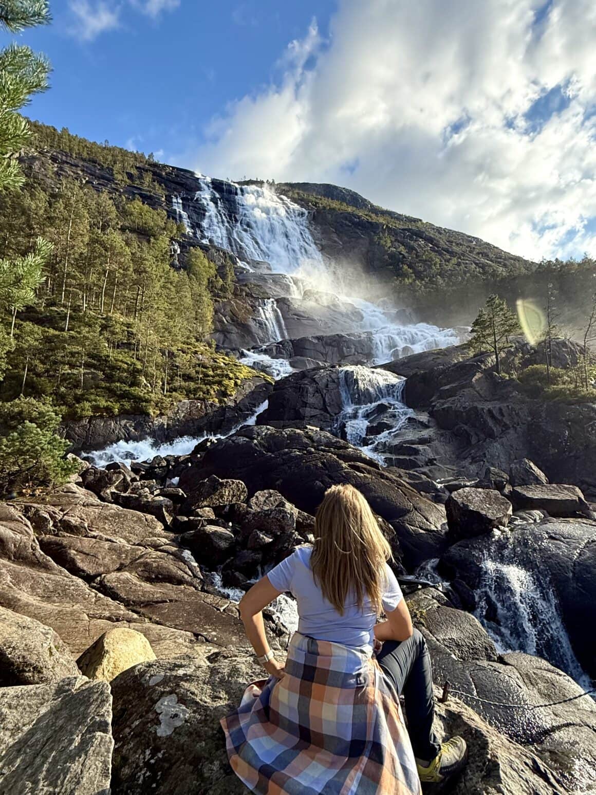 Wodospad szumi, słońce grzeje skały, a fiord lśni w dole — dokładnie tak wygląda definicja „nie wracam do domu”.