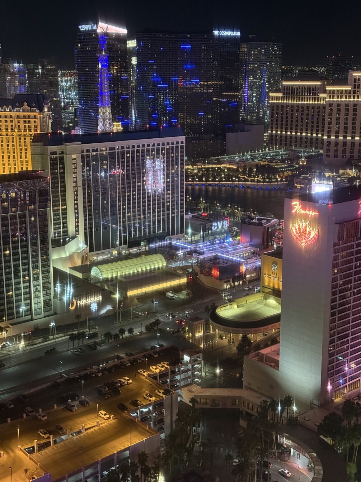 Widok z okna… gdyby okno było teleportem 🌃✨ Panorama z góry to dowód, że miasto żyje nawet wtedy, gdy ty masz już czwarty zjazd energetyczny. Neonowe rzeki płyną w dół ulic, a każdy hotel mruga własnym rytmem — jakby brał udział w konkursie na „najbardziej widoczną budowlę wszech czasów”.